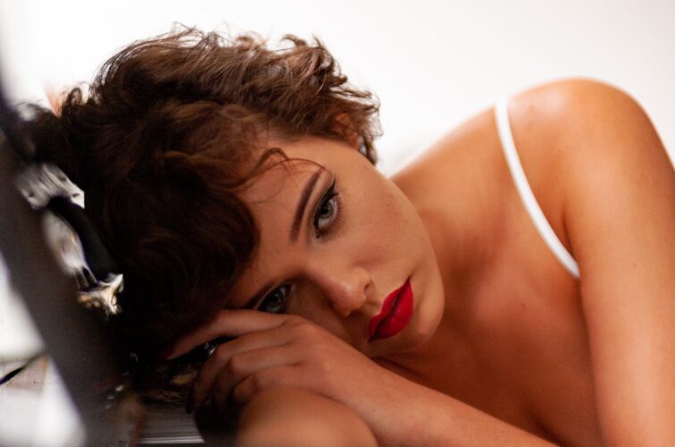 Model with an elegant red manicure resting at a piano, at Armani Nail Boutique, the best in the heart of Vancouver.
