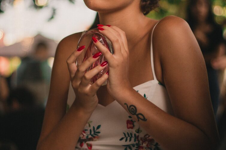 Model with a sophisticated red manicure and makeup holding a decorative object, at Armani Nail Boutique, the best in the heart of Vancouver.