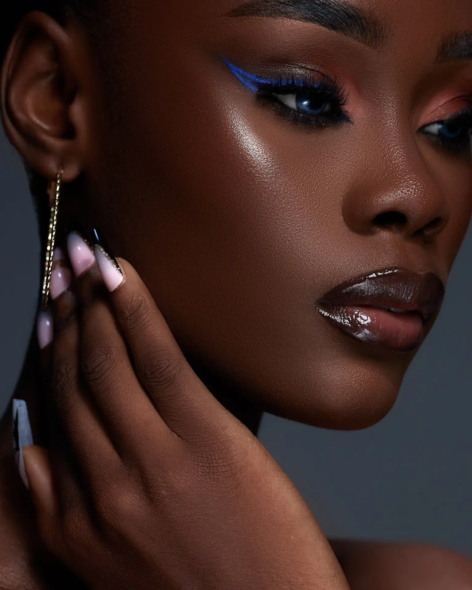 Close-up beauty portrait featuring a person with glowing skin, dramatic blue eyeliner, glossy lips, and ombre nails, seen at armaninail.com