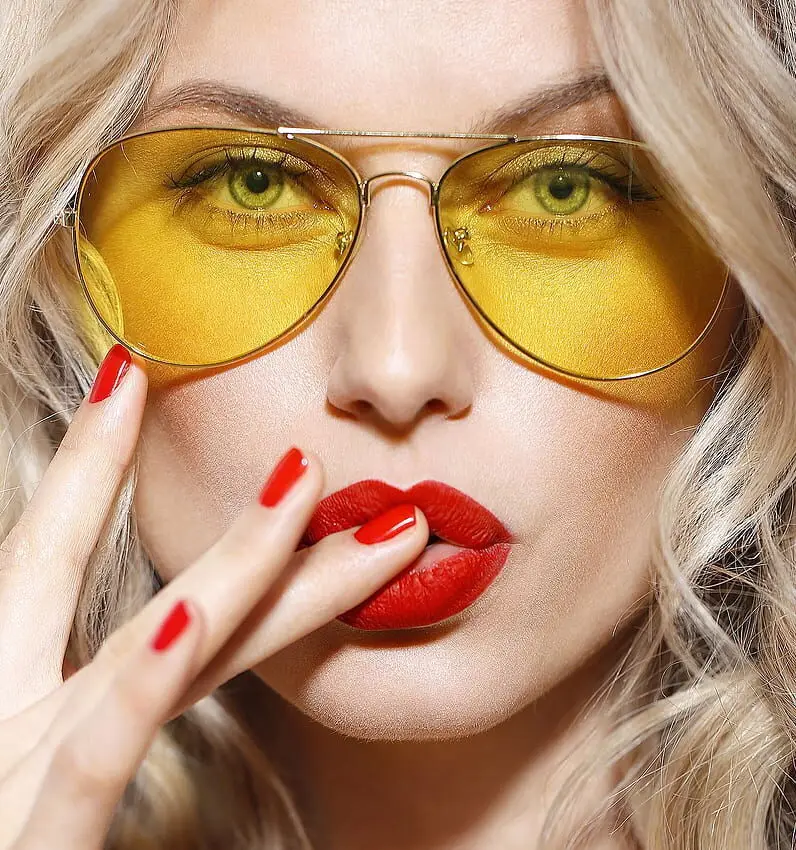 Close-up of a model with classic red nail polish and stylish yellow sunglasses, at Armani Nail Boutique, the best in the heart of Vancouver.