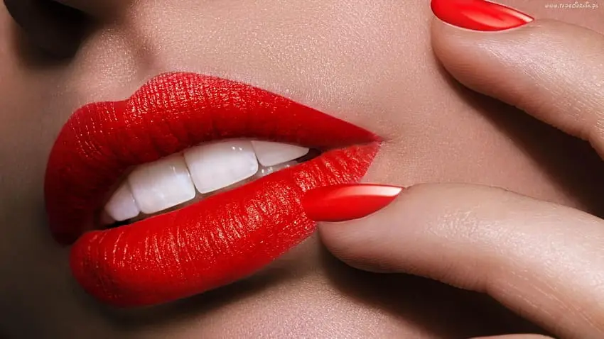 Close-up of a model with a glossy red manicure and matching red lips, at Armani Nail Boutique, the best in the heart of Vancouver.